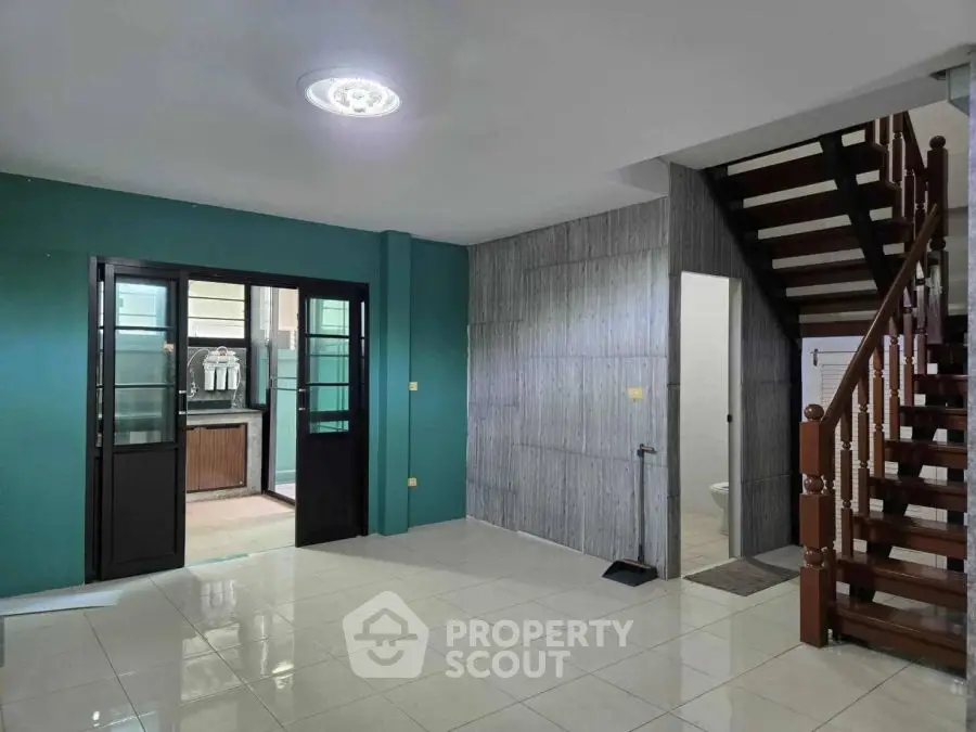 Spacious living area with modern staircase and open kitchen view