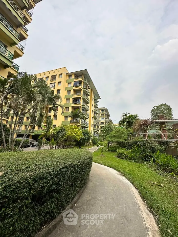 Charming residential building with lush garden pathway and palm trees