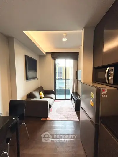 Modern compact living room with balcony access and sleek kitchen appliances.