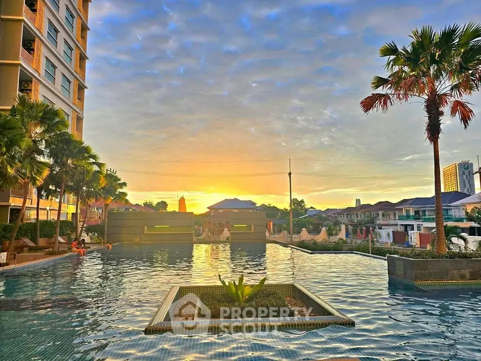 Stunning sunset view over a luxurious apartment pool with palm trees and skyline.
