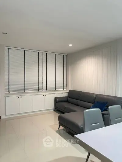Modern living room with sleek leather sofa and stylish blinds, perfect for contemporary living.
