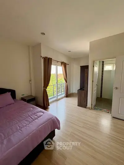 Spacious bedroom with balcony access and en-suite bathroom, featuring modern decor and natural light.