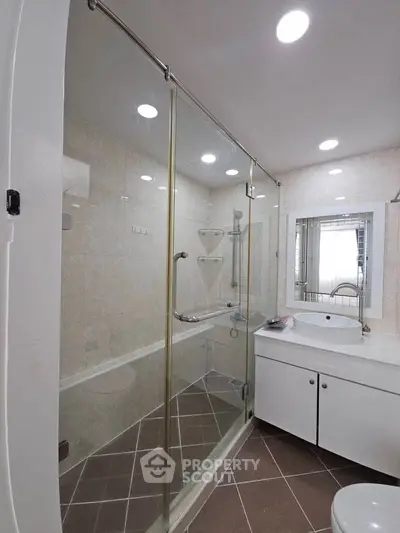 Modern bathroom with glass shower enclosure and sleek vanity in a contemporary home.