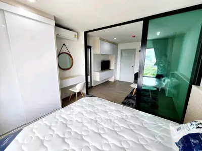 Modern bedroom with sliding glass doors and city view, featuring sleek furniture and a comfortable mattress.