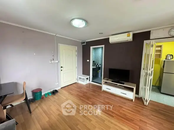 Spacious living room with wooden flooring, modern furniture, and air conditioning in a cozy apartment.