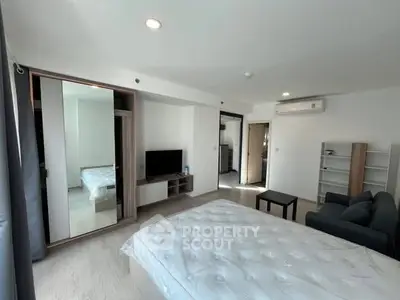 Spacious modern bedroom with mirrored wardrobe and cozy seating area