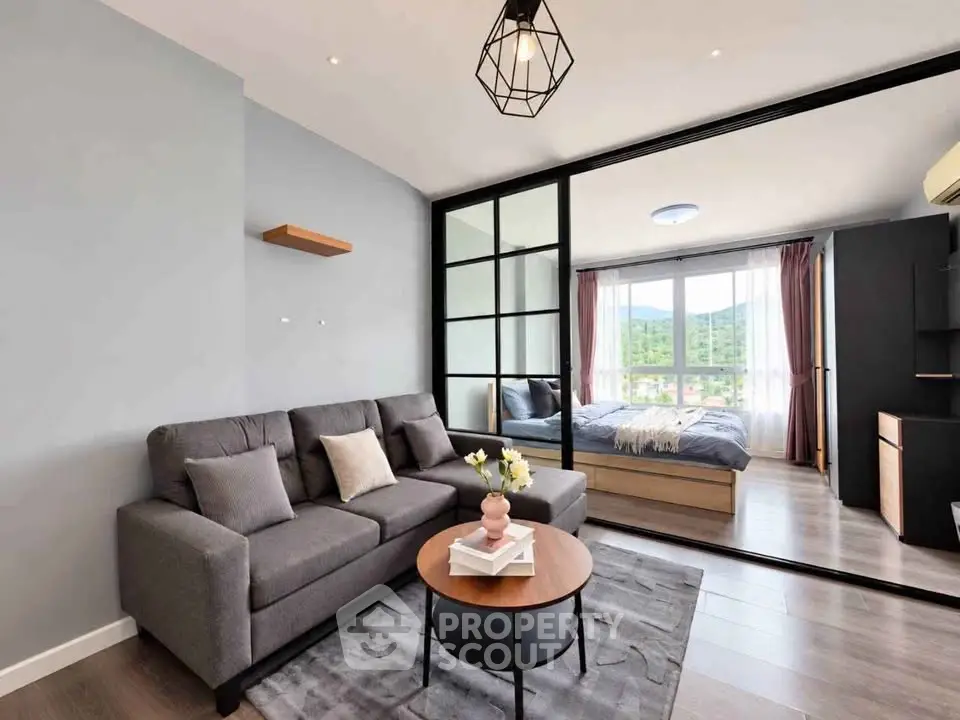Modern living room with stylish decor and a view into a cozy bedroom