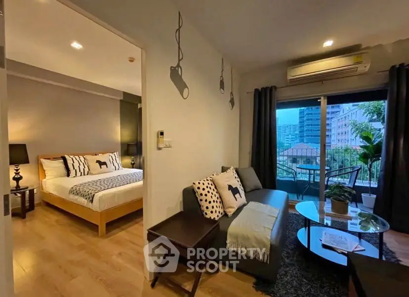 Modern apartment with cozy living room and bedroom, featuring a balcony with city view.