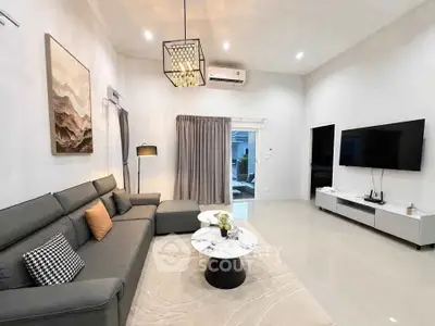 Spacious modern living room with elegant decor and large TV, perfect for relaxation and entertainment.