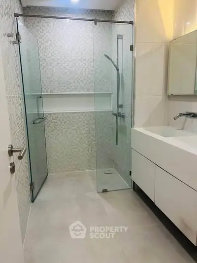 Modern bathroom with glass shower and sleek vanity in contemporary design.