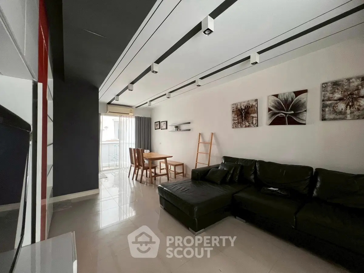 Modern living room with sleek black sofa, dining set, and stylish decor.
