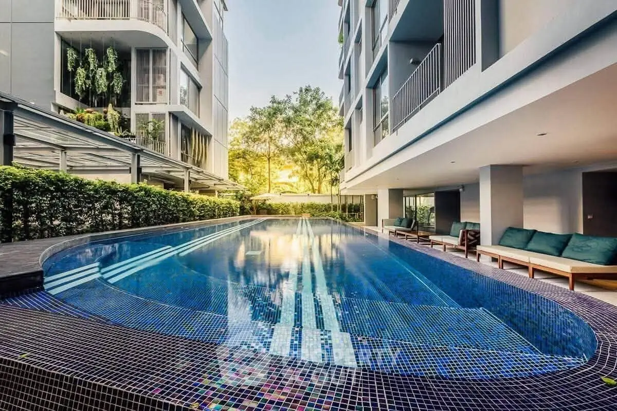 Luxurious modern apartment complex with stunning outdoor pool and lush greenery.