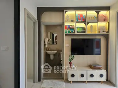 Modern living room with stylish shelving and wall-mounted TV, adjacent to a compact bathroom.