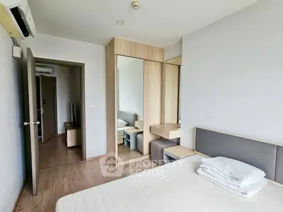 Modern bedroom with minimalist design and wooden flooring, featuring a built-in wardrobe and cozy bed.
