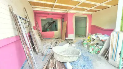 Spacious under-construction property with vibrant pink walls and ample renovation materials.