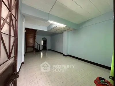 Spacious unfurnished room with tiled floor and staircase, ideal for customization.