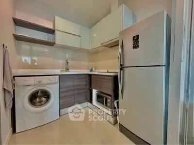 Modern kitchen with sleek cabinets, washing machine, and stainless steel fridge in compact layout.