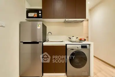 Modern compact kitchen with stainless steel fridge and washing machine in cozy apartment.