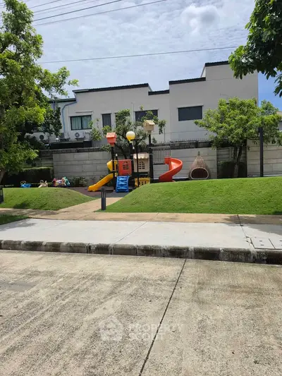 Charming residential playground with vibrant slides and lush greenery, perfect for family-friendly living.