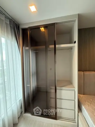 Modern bedroom with sleek wardrobe and natural light from large window.