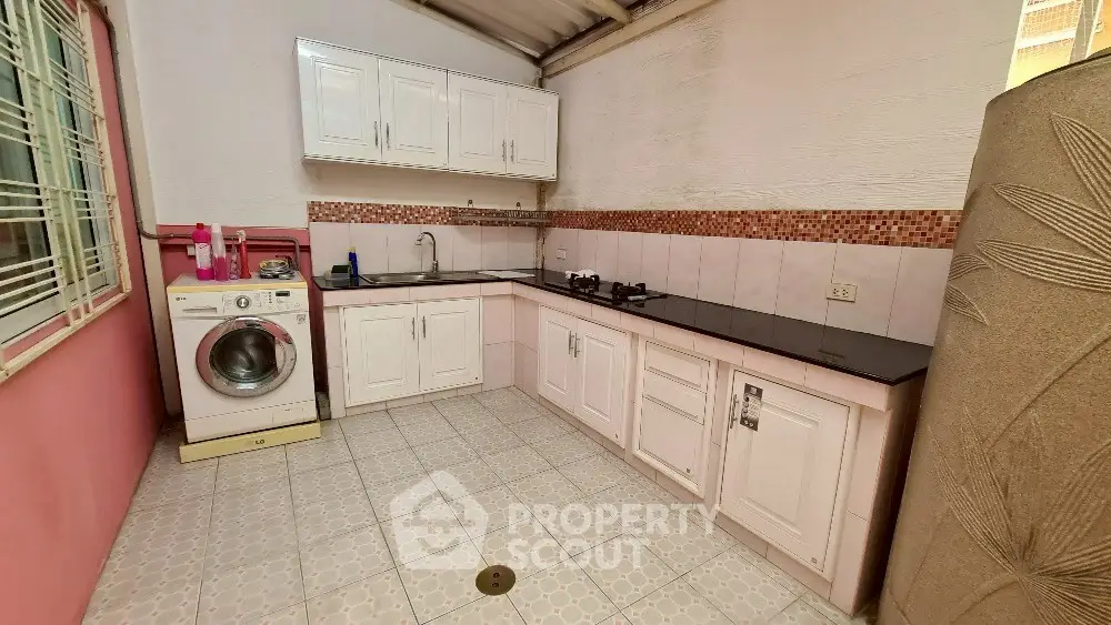 Spacious kitchen with washing machine and gas stove in modern home