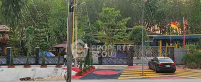 Luxurious gated property with modern design and lush greenery, featuring a sleek black car parked in front.