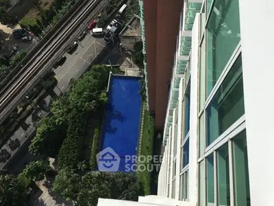 Stunning aerial view of modern building with luxurious pool and lush greenery, perfect for urban living.