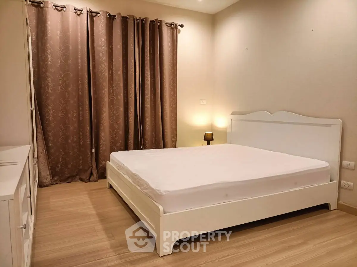 Spacious bedroom with elegant white bed and warm lighting, perfect for relaxation.