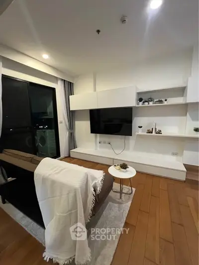 Modern living room with sleek design, featuring a wall-mounted TV, cozy sofa, and stylish shelving.