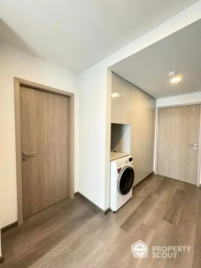 Modern hallway with sleek wooden flooring and built-in laundry area