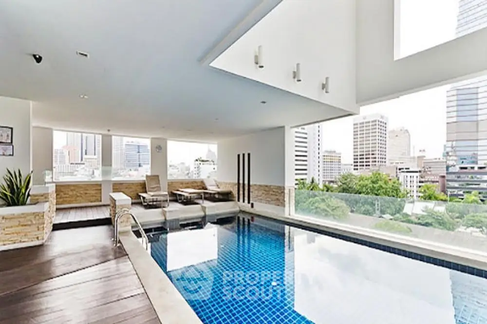 Luxurious indoor pool with city skyline view in modern high-rise building.