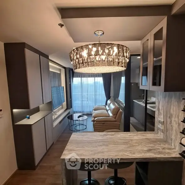 Luxurious living room with elegant chandelier and modern open kitchen layout.