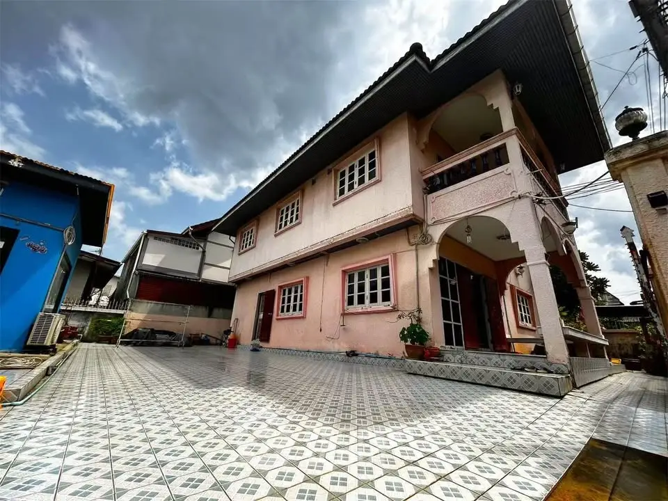 Charming two-story house with tiled courtyard and covered balcony, perfect for family living.