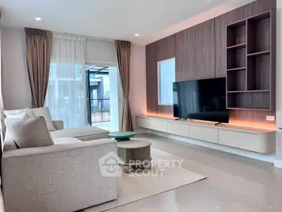 Modern living room with sleek design, large TV, and natural light from balcony.
