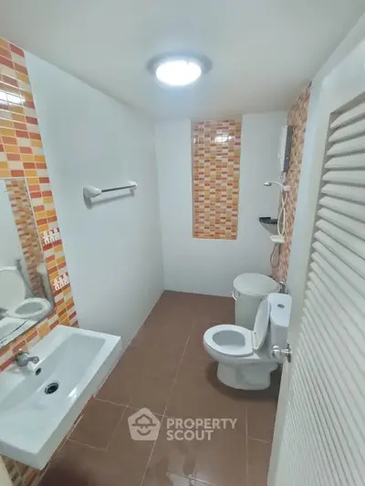 Modern bathroom with stylish orange tile accents and sleek fixtures.