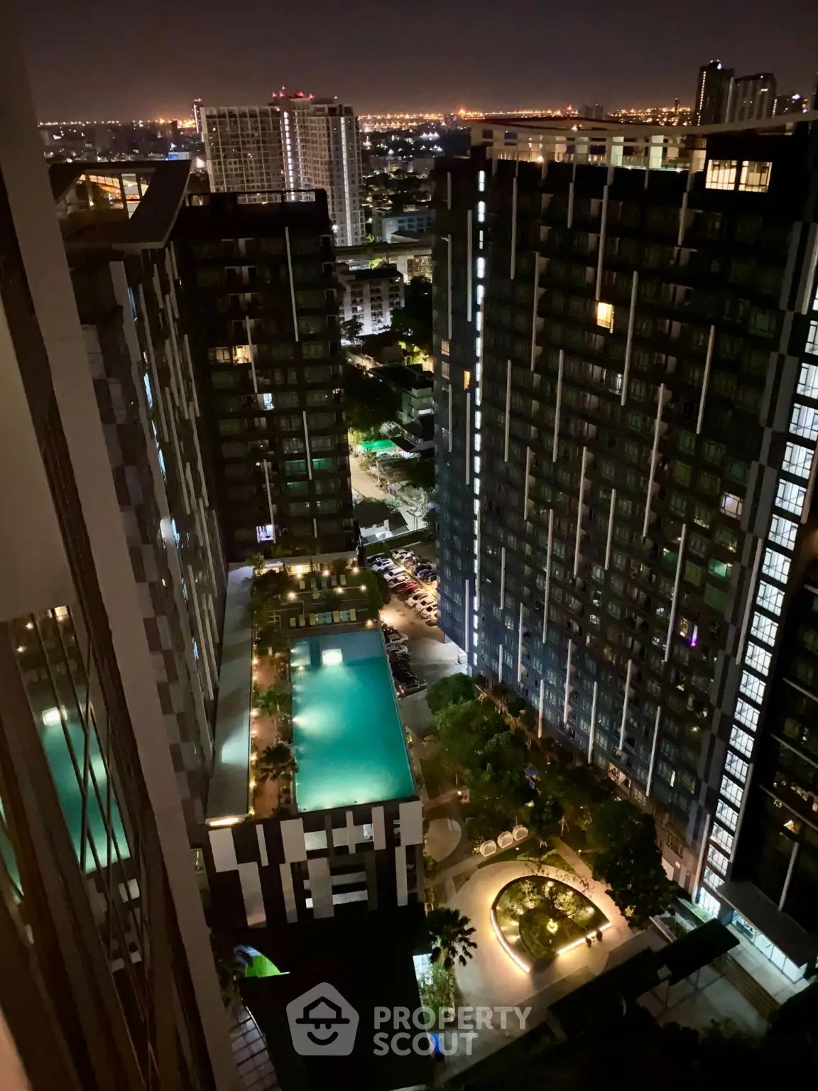 Stunning night view of modern high-rise buildings with illuminated pool and cityscape.