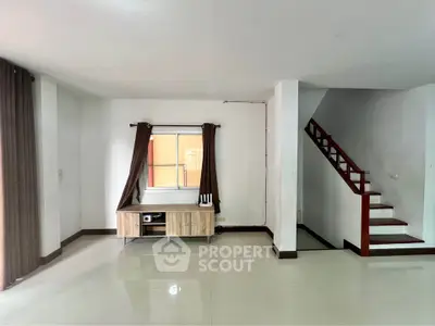 Spacious living room with modern staircase and natural light