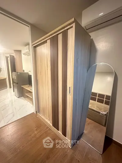 Modern bedroom with wooden wardrobe and sleek mirror, featuring air conditioning for comfort.