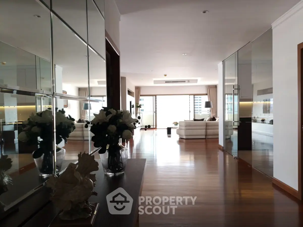 Spacious modern living room with elegant decor and large windows offering city views.