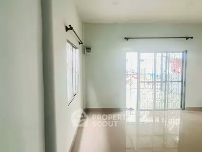 Spacious living room with large windows and glossy tiled floors, offering ample natural light and a modern ambiance.