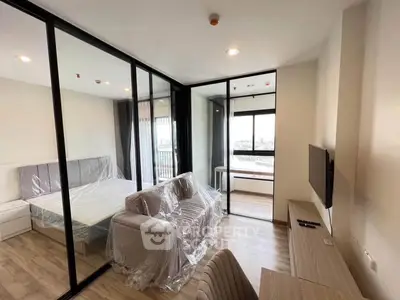 Modern apartment with glass partition, cozy living area, and city view balcony.