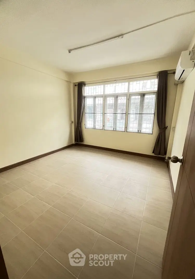 Spacious empty room with large windows and tiled flooring, perfect for customization.