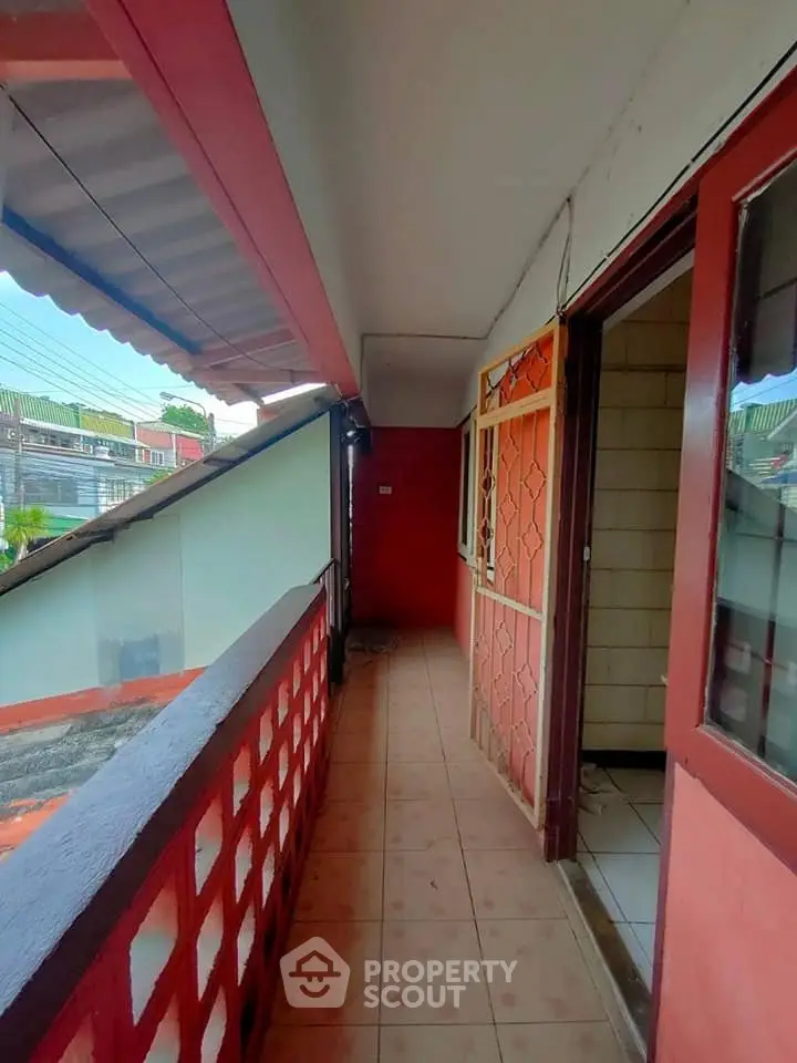 Charming balcony with tiled flooring and red accents, offering a cozy outdoor space with neighborhood views.
