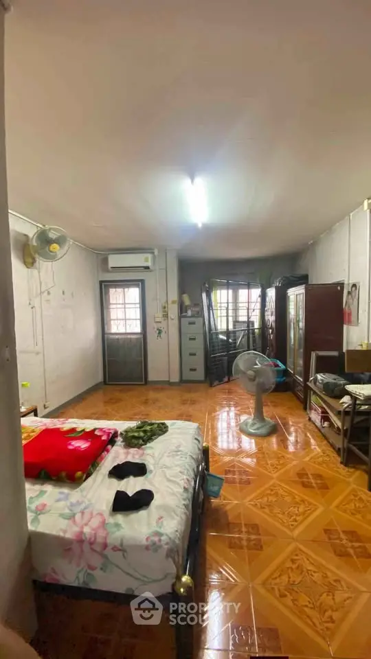 Cozy bedroom with tiled floor, bed, fan, and natural light from window.