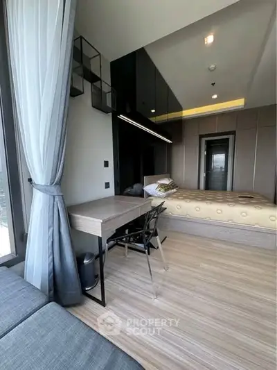 Modern bedroom with stylish decor and natural light, featuring a cozy bed and sleek desk area.