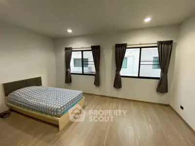 Spacious bedroom with wooden flooring and large windows for natural light.