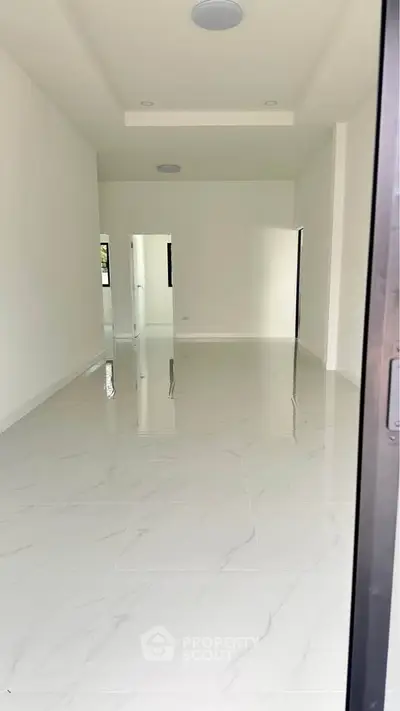 Spacious empty room with glossy white tiles and high ceiling, ideal for customization.