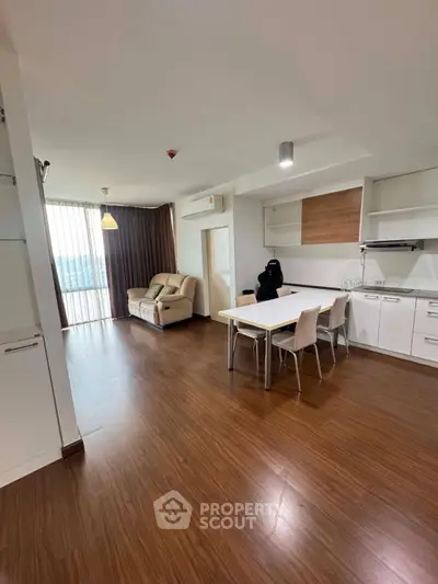 Spacious modern living room with open kitchen and large windows offering natural light.