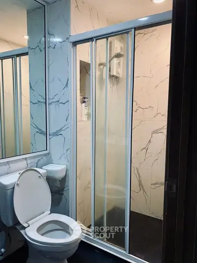 Modern bathroom with marble walls and glass shower enclosure