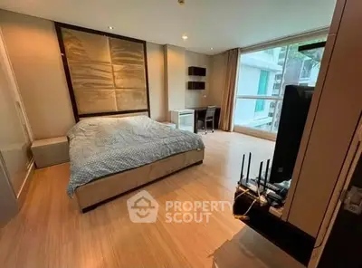 Spacious bedroom with modern decor and large window offering natural light and city view.